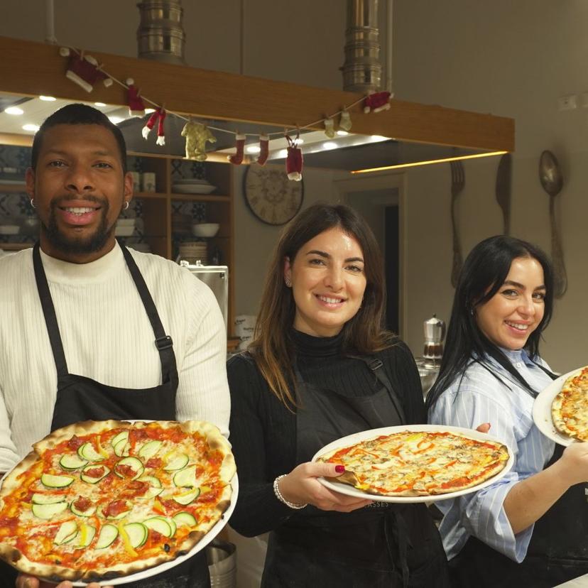 Participants smiling and holding homemade pizzas during a pizza and gelato class in Rome