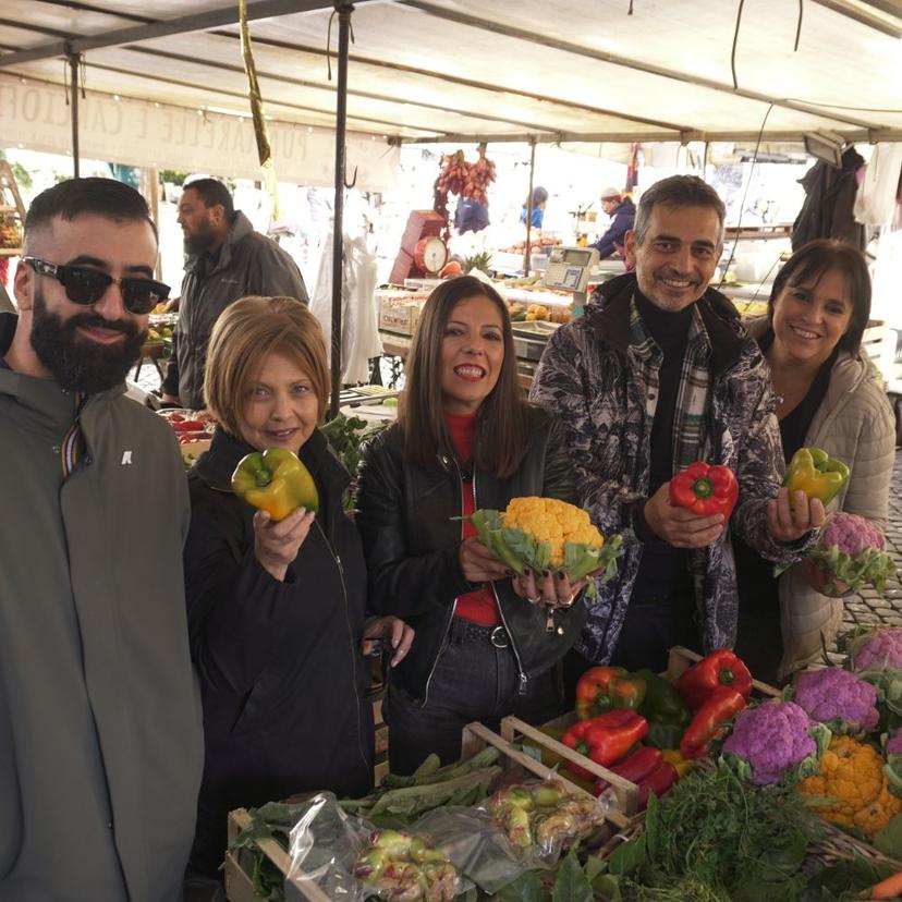 Farmers market vegetable shopping for Sunday Lunch class Guests holding fresh vegetables at a farmers market during the Italian Sunday Lunch shopping experience with InRome Cooking